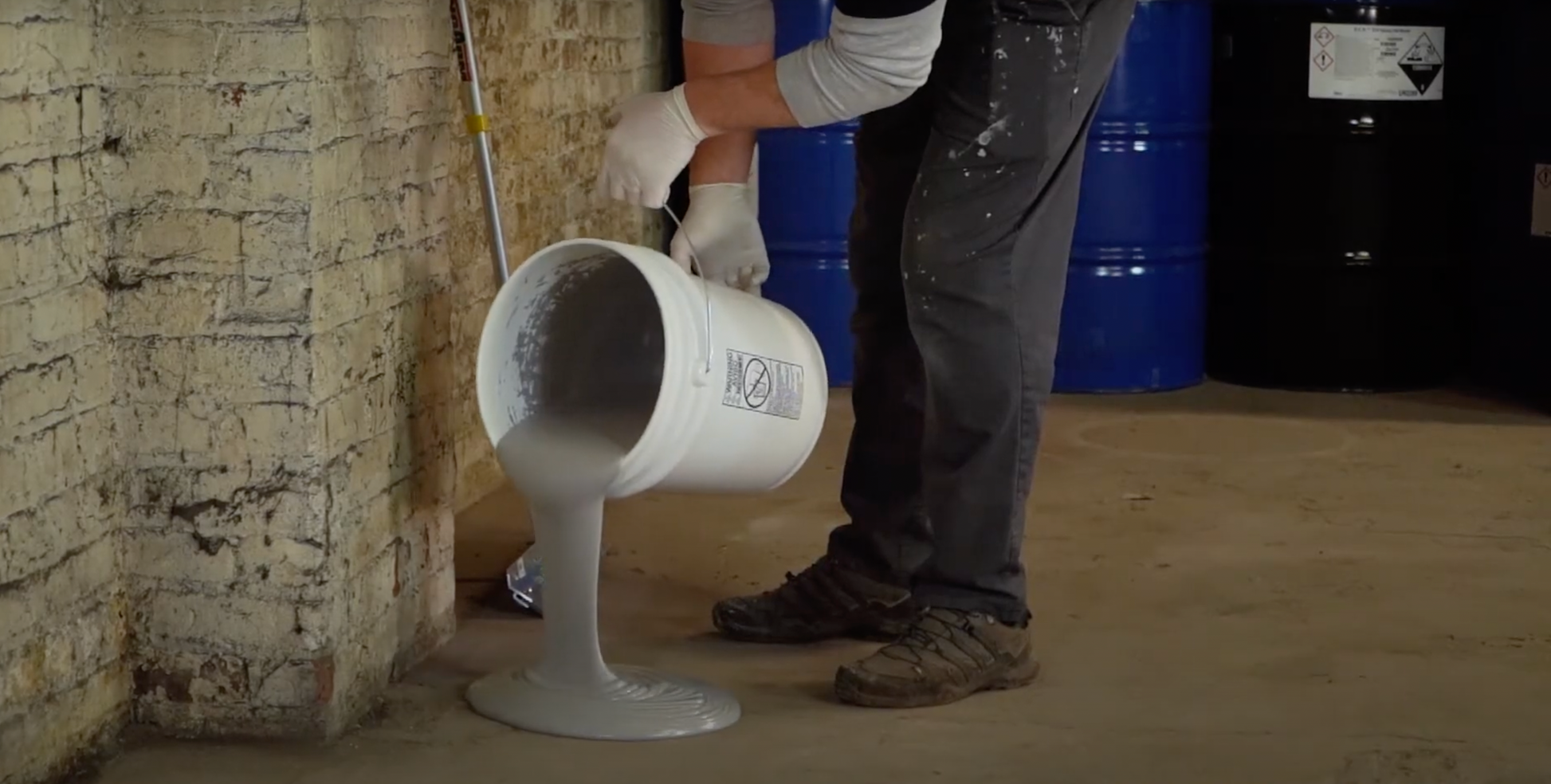 Pouring zipcrete epoxy topcoat onto a concrete floor